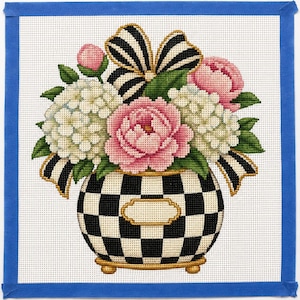 May include: A needlepoint canvas featuring a bouquet of pink peonies and white hydrangeas in a black and white checkered vase. The arrangement is accented with a black and white striped bow and green leaves, all set against a white grid background.