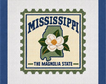 May include: A needlepoint canvas featuring a postage stamp design with the text MISSISSIPPI and THE MAGNOLIA STATE. The center displays a green outline of the state of Mississippi with a white magnolia flower and green leaves, framed by a blue border.