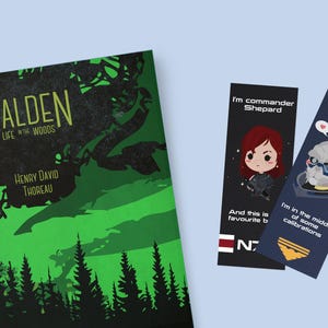 Puede incluir: Un libro titulado "Walden" con un diseño de bosque verde y negro, y dos marcadores. Un marcador presenta una caricatura de una mujer con el texto "I'm commander Shepard". El otro marcador tiene un robot con el texto "Can it wait for a bit?"