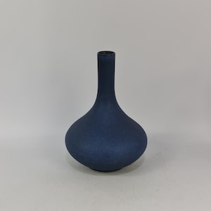 Puede incluir: Un jarrón de cerámica azul oscuro con una base redonda y un cuello estrecho.