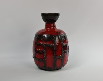 Pode incluir: Um vaso de cerâmica vermelho com um esmalte preto e um padrão geométrico. O vaso tem um corpo arredondado e um pescoço estreito.
