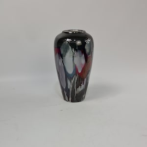 Puede incluir: Un jarr&oacute;n decorativo alto con acabado negro brillante. El jarr&oacute;n presenta un dise&ntilde;o &uacute;nico con vetas blancas, grises, rojas y moradas. Tiene un cuello estrecho y un cuerpo m&aacute;s ancho, ideal para flores o como pieza decorativa.