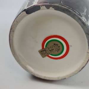 Puede incluir: Un jarr&oacute;n de cer&aacute;mica con interior blanco y exterior oscuro con dise&ntilde;o veteado. La base del jarr&oacute;n tiene una pegatina con los colores de la bandera italiana y la inscripci&oacute;n "MADE IN ITALY".