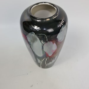 Puede incluir: Un jarr&oacute;n decorativo con un acabado negro brillante y una abertura ancha. El jarr&oacute;n presenta detalles abstractos grises, blancos y rosas. El interior es blanco. Este jarr&oacute;n es adecuado para la decoraci&oacute;n del hogar.