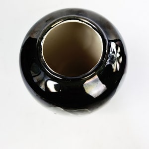 Puede incluir: Un jarr&oacute;n de cer&aacute;mica negro brillante con cuerpo redondo y boca ancha. El interior es de color marr&oacute;n claro, contrastando con el exterior. El jarr&oacute;n est&aacute; sobre un fondo blanco.