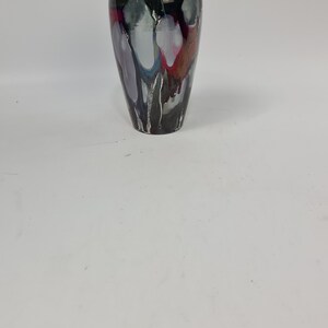 Puede incluir: Un jarr&oacute;n decorativo con un acabado negro brillante y un dise&ntilde;o abstracto &uacute;nico. El jarr&oacute;n presenta vetas blancas, grises, moradas y rojas, creando un efecto visual llamativo. Tiene un cuello estrecho y un cuerpo m&aacute;s ancho, ideal para arreglos florales.