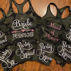 May include: Camouflage print tank tops and matching shorts. The tank tops have white or pink glitter text that says "Bride", "Maid of Honor", and "Party Squad". The bride's tank top says "THE HUNT IS OVER".