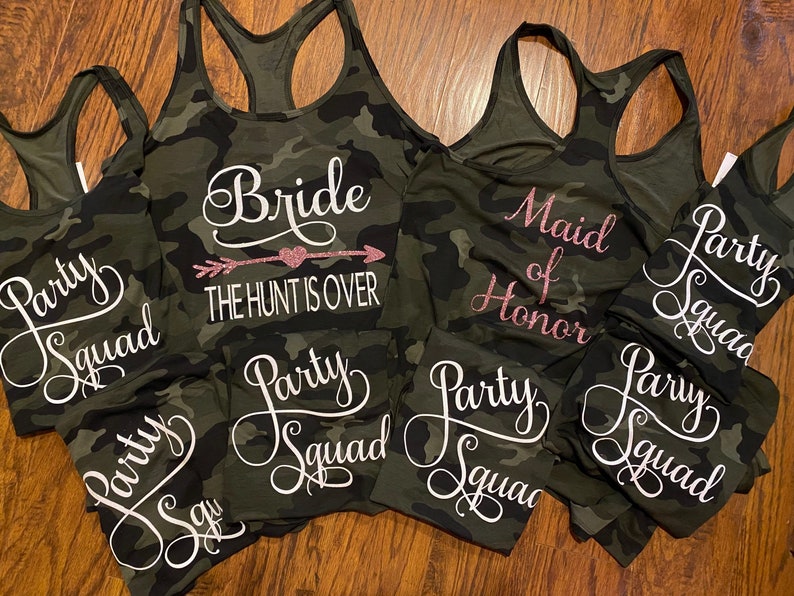 May include: Camouflage print tank tops and matching shorts. The tank tops have white or pink glitter text that says "Bride", "Maid of Honor", and "Party Squad". The bride's tank top says "THE HUNT IS OVER".