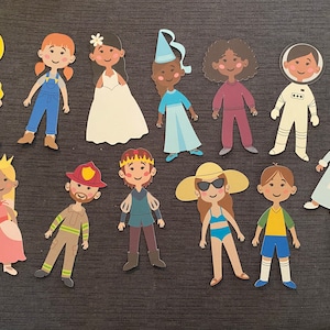 Puede incluir: Un conjunto de 13 muñecas de papel, cada una con un atuendo y un peinado diferentes. Las muñecas son todas sonrientes y tienen diferentes tonos de piel. Los atuendos incluyen un impermeable amarillo, un vestido de peto azul, un vestido de novia blanco, un vestido de princesa azul, un suéter rojo y pantalones, un traje de astronauta blanco, una bata azul, un vestido de princesa rosa, un uniforme de bombero rojo, un traje de caballero azul y verde, un traje de baño, una camiseta amarilla y pantalones cortos azules, y un sombrero blanco y gafas de sol.