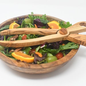 以下が含まれることがあります： 木製のサラダボウルに、グリーン、オレンジのスライス、ブドウ、ペカンナッツが入ったサラダが入っています。木製サラダトングもセットになっています。