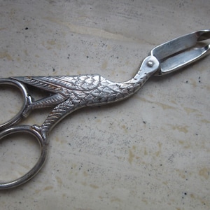 Puede incluir: Pinzas de azúcar plateadas con diseño de pájaro. Las pinzas presentan un motivo detallado de pájaro en el mango y un mecanismo de tijera para agarrar. Estas pinzas vintage están diseñadas para servir terrones de azúcar.