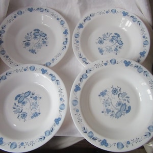 Puede incluir: Juego de cuatro cuencos de cerámica blanca con diseños florales azules. Los cuencos tienen un borde festoneado y un borde ancho.