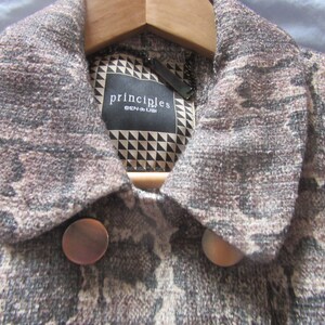 May include: A brown and beige patterned jacket with a collar and two buttons. The jacket has a label that says "principles" and "BEN DE LISI".