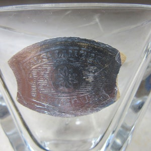 May include: A clear glass triangular dish with a silver sticker on the bottom. The sticker has a design of a flower with a star in the centre and the text "Made in France" around the edge.