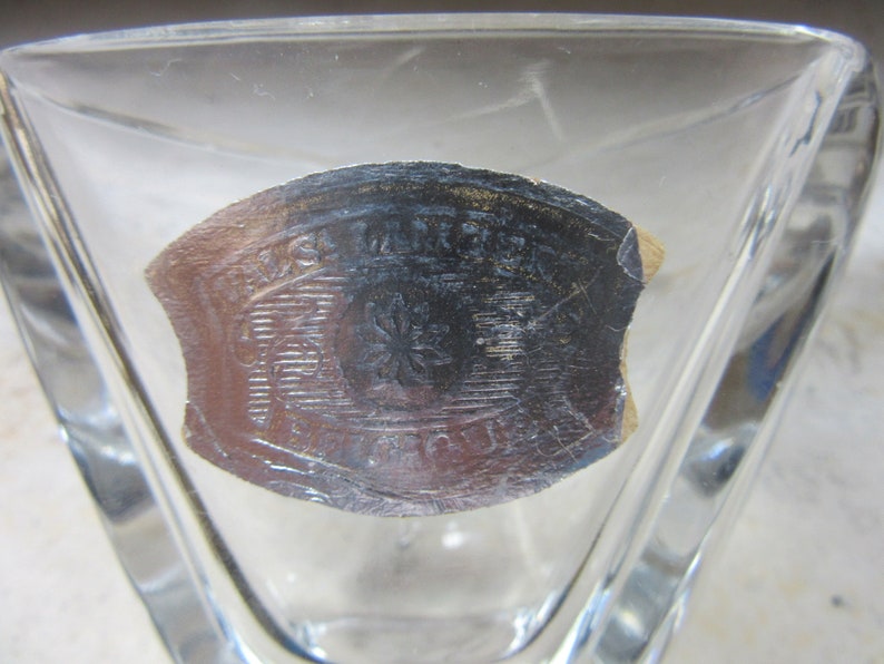 May include: A clear glass triangular dish with a silver sticker on the bottom. The sticker has a design of a flower with a star in the centre and the text "Made in France" around the edge.