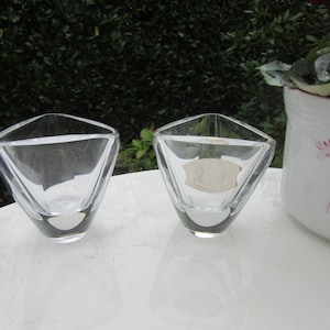 May include: Two clear glass bowls with a geometric design. The bowls are sitting on a white surface.