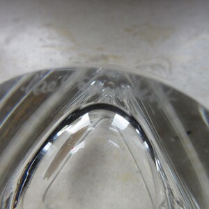 May include: Close-up of the base of a clear glass vase with a decorative etched design. The etching reads "Made in France".