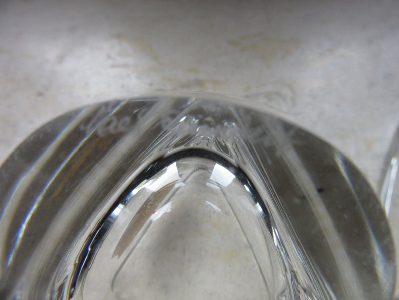 May include: Close-up of the base of a clear glass vase with a decorative etched design. The etching reads "Made in France".
