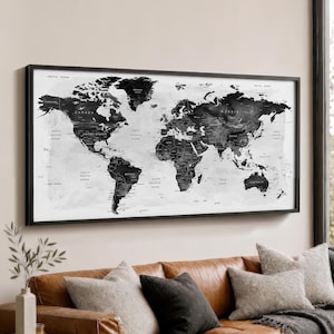 May include: A rectangular wall art piece featuring a detailed world map in shades of black, gray, and white. The map displays continents, countries, and oceans with clear text labels for geographical locations, all enclosed in a thin black frame.