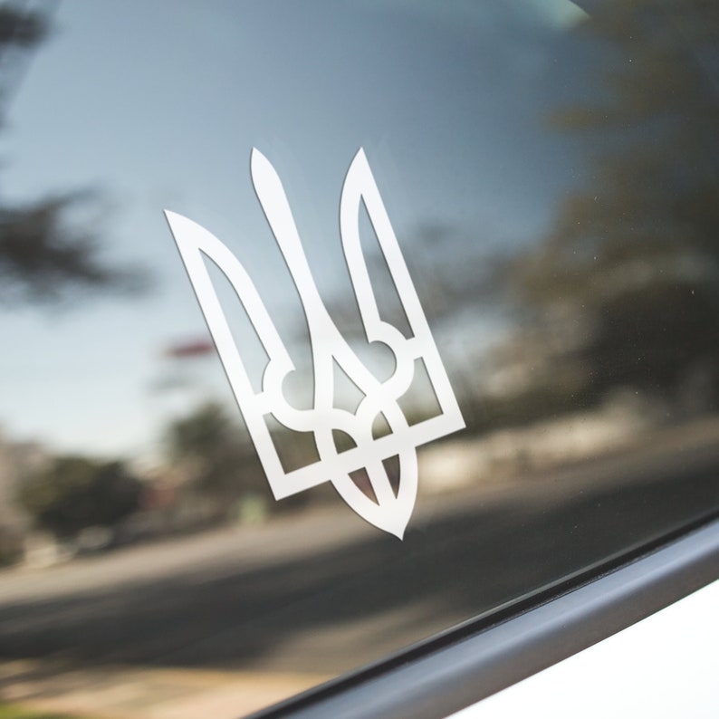 May include: White vinyl sticker of the Ukrainian coat of arms, the Tryzub, on a car window.