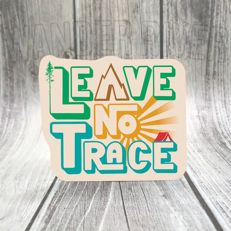 May include: A beige sticker with the text "Leave No Trace" in green, blue, and orange letters. The text is stylized with a 3D effect. The sticker features a small pine tree, a mountain, a sun, and a red tent.