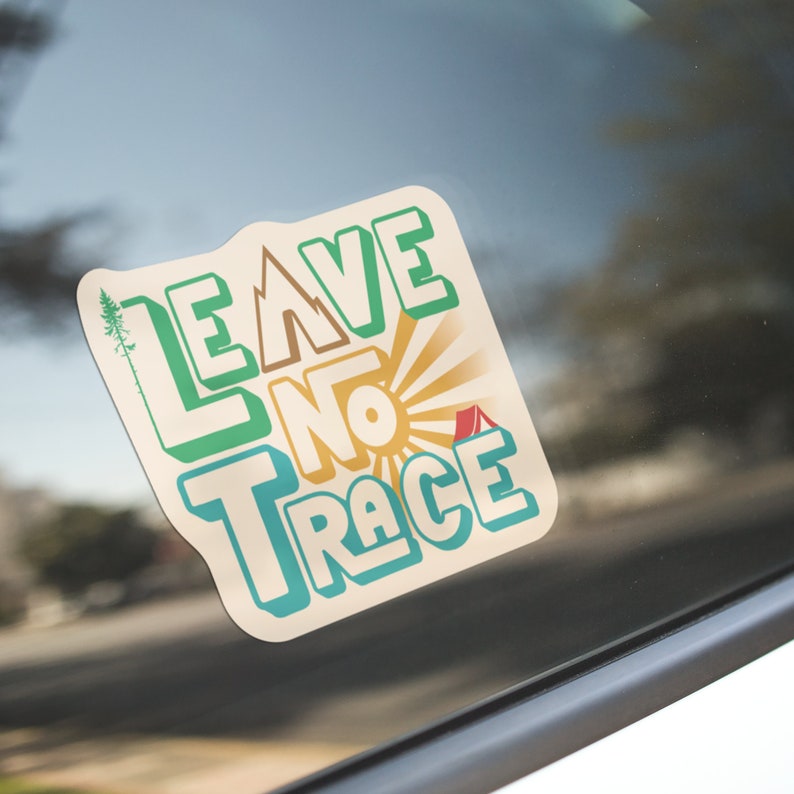 May include: A sticker with a retro design that says "Leave No Trace" in green, yellow, and blue lettering. The sticker has a sunburst design and a small red tent.