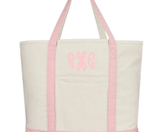 May include: A large, white canvas tote bag with pink trim and handles. The bag has a pink monogram on the front that reads "R.K.G."