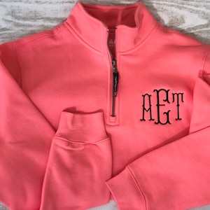 May include: A coral colored quarter zip sweatshirt with a black embroidered monogram "MET" on the front.