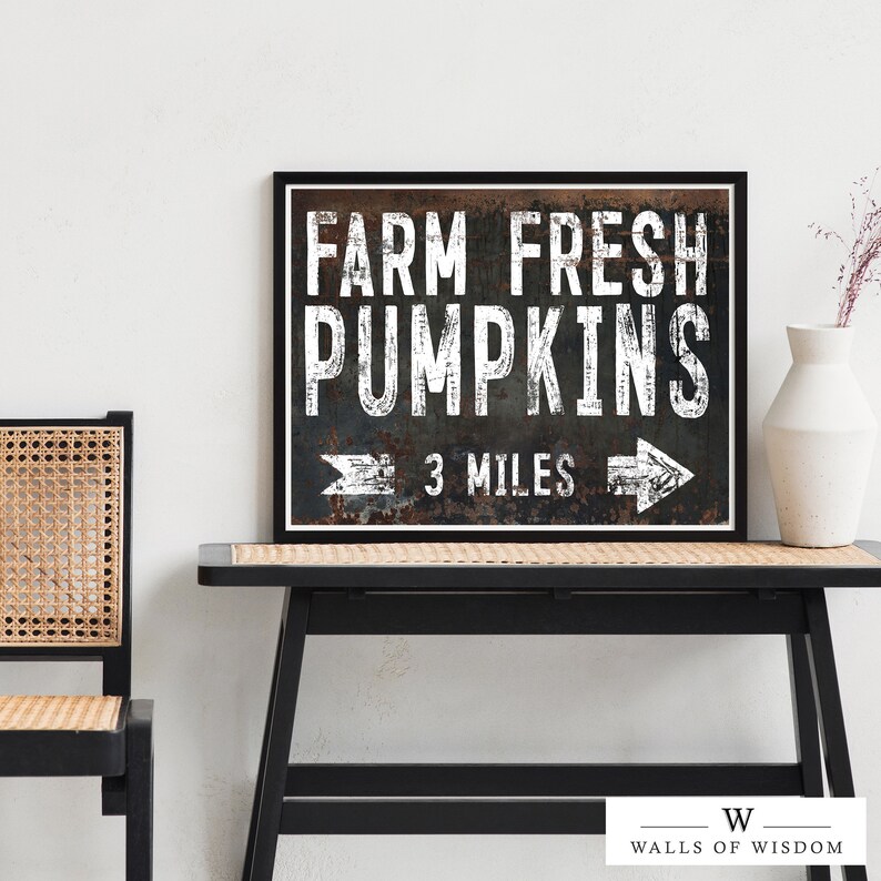 May include: A black framed sign with white text that reads "Farm Fresh Pumpkins 3 Miles" with a rusty metal background and arrows pointing left and right.