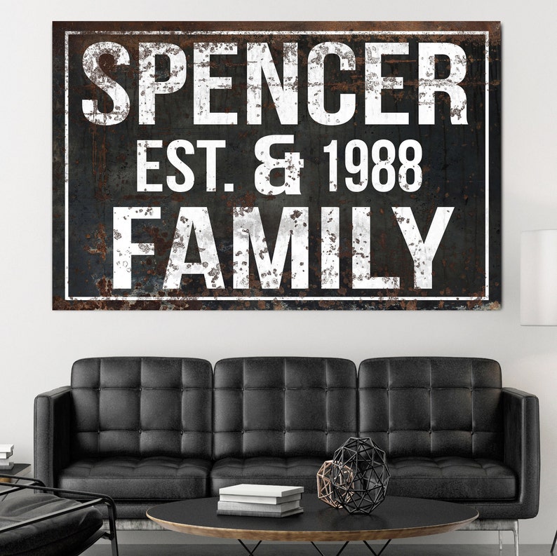 Puede incluir: Un letrero en blanco y negro con un aspecto de metal desgastado. El letrero dice "Spencer Est. & 1988 Family".