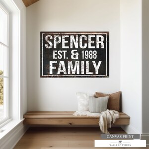 Puede incluir: Una impresi&oacute;n en lienzo de estilo r&uacute;stico con el texto "Spencer Est. & 1988 Family" en letras blancas sobre fondo negro. La impresi&oacute;n tiene un aspecto desgastado y envejecido, lo que le da un toque vintage.