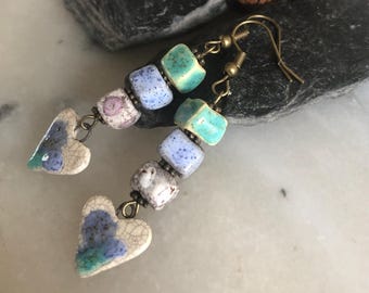 Pendientes inspirados en la Tierra y la Naturaleza, cerámica artesanal, cubos y corazones, tonos suaves de blanco, azul y turquesa, cuentas de metal.
