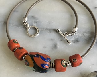 Short ethnic necklace, boho chic, Indonesian ceramic, African glass paste, brick tones, lapis blue, orange green, khaki leather cord