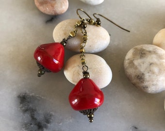 Dangling earrings, boho-chic, raku ceramic beads, dark red, black background, golden bronze-colored metal chains.