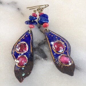 May include: A pair of blue and gold earrings with pink and blue gemstone accents. The earrings are made of metal and have a unique, organic shape.
