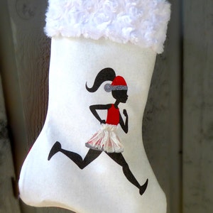 May include: White Christmas stocking with a red and white fur cuff. The stocking features a black silhouette of a girl running, wearing a red dress and a Santa hat.