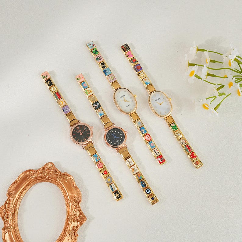 May include: Four gold-coloured wristwatches with decorative straps and oval faces. The watch faces are black or white. The straps feature colourful, square charms. The watches are arranged diagonally on a white surface, with a decorative gold frame in the lower left corner.