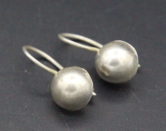 May include: A pair of silver hoop earrings with a smooth, round ball design.