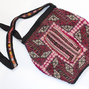 Puede incluir: Un bolso tote rojo, negro y blanco con estampado con una larga correa negra. El bolso tiene un diseño geométrico con bordados intrincados.