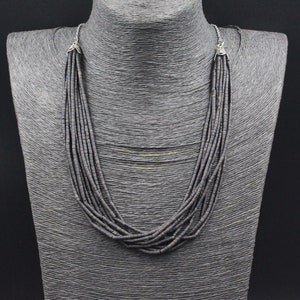 Peut inclure: Un collier multi-rangs composé de perles gris foncé. Le collier est sur un mannequin et a des fermoirs argentés.