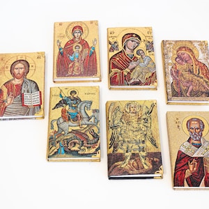 Könnte beinhalten: Eine Sammlung kleiner, rechteckiger religiöser Ikonen mit goldfarbenen Hintergründen. Die Ikonen zeigen verschiedene religiöse Figuren, darunter Jesus, Maria und das Jesuskind sowie Heilige. Die Bilder sind detailliert und farbenfroh, mit einer Vintage-Ästhetik.