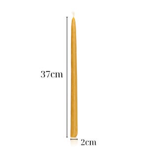 May include: A tall, slender yellow taper candle with a visible white wick at the top. The candle is displayed with measurement indicators showing a height of 14.57 inches and a base diameter of 0.79 inches, providing clear scale for the object.