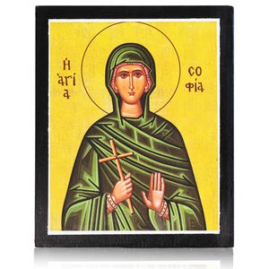 Könnte beinhalten: Religiöse Ikone mit einer Frau in einem grünen Gewand, die ein Holzkreuz hält. Das Bild hat einen gelben Hintergrund mit einem goldenen Heiligenschein und griechischem Text. Die Ikone ist in einen schwarzen Holzrahmen gefasst.