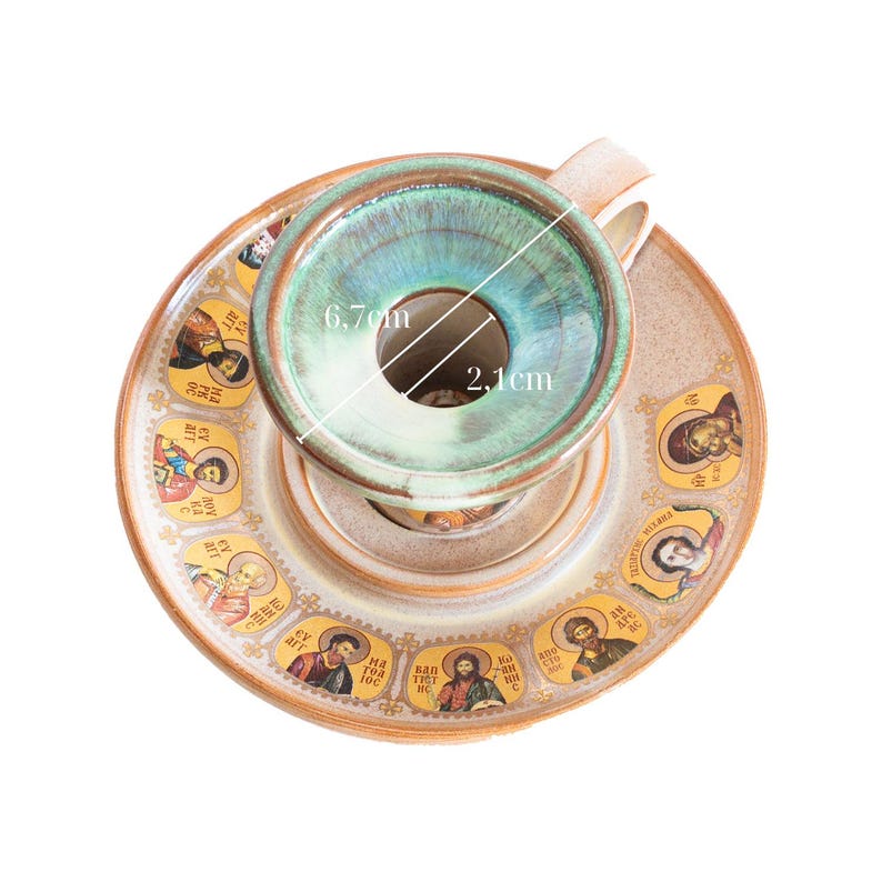 May include: A ceramic cup and saucer set featuring a teal glazed interior and a rim decorated with multiple religious icon portraits. The cup has a 6.7 cm outer diameter and a 2.1 cm inner diameter, as indicated by the white measurement lines.