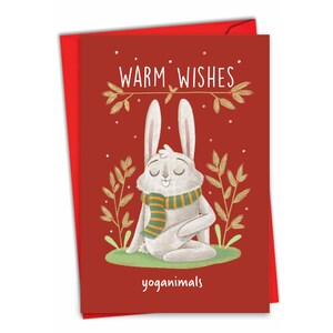 May include: A red greeting card with a white rabbit in a yoga pose, wearing a green and gold scarf. The card reads "Warm Wishes" and "yoganimals" in white text. The card is set against a red envelope.