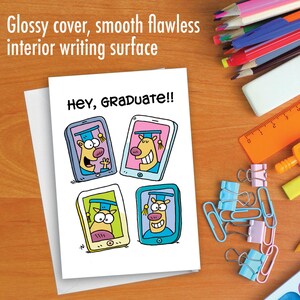 May include: A white card with a glossy cover and a smooth writing surface. The card has a colorful cartoon illustration of four animals wearing graduation caps and looking out of cell phones. The text "Hey, Graduate!!" is written in black at the top of the card.