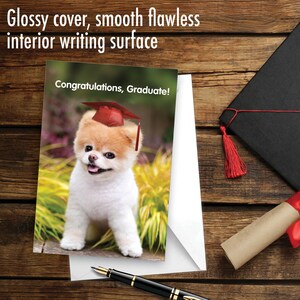 May include: A graduation card featuring a cute white dog wearing a red graduation cap. The card has a glossy cover and a smooth writing surface. The text on the card reads "Congratulations, Graduate!"