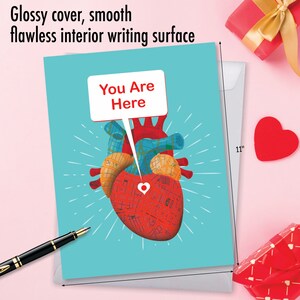 May include: A turquoise card with a red heart made of a map with a red pin in the center. The heart has a speech bubble above it that says "You Are Here".