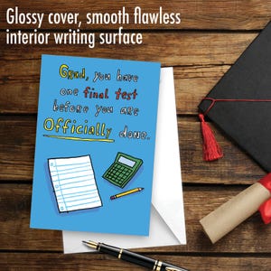 May include: A blue greeting card with a cartoon illustration of a calculator, pencil, and a sheet of paper. The text on the card reads "Grad, you have one final test before you are Officially done."