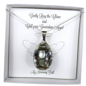 May include: A silver necklace with an oval pendant. The pendant is made of iridescent abalone shell pieces and silver-toned metal. The packaging includes the text "Gently Ring the Chime and Call your Guardian Angel" and "My Harmony Ball."